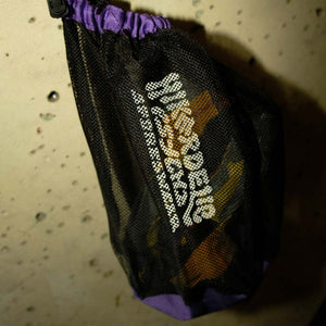 A purple and black webbed climbing shoe bag hangs from a climbing hold at Parthian Climbing Centre in Manchester.