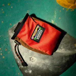 Burnt orange and brown corduroy climbing chalk bag sits on a bouldering hand hold at Parthian Climbing Centre in manchester