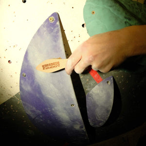 A climber cleans climbing chalk off a hand hold at Parthian Climbing Centre in Manchester.