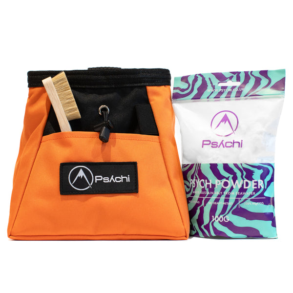 An orange bouldering chalk bag and chalk with wooden climbing brush.