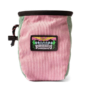 A muted pink and light green corduroy rock climbing chalk bag with sunset mountain scene patch and drawstring closure.