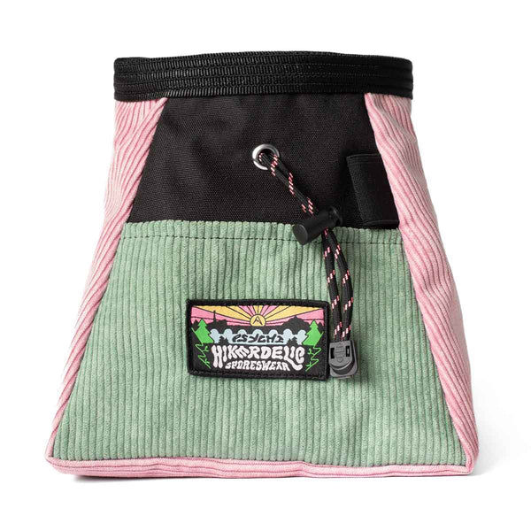 A muted pink, light green and black corduroy climbing chalk bucket bag with drawstring closure and an elastic brush holder.