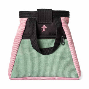 A muted pink, light green and black corduroy climbing chalk bucket bag with a zip closure accessory pocket and black carry handle.