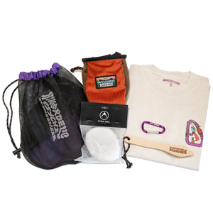 An orange and brown climbing chalk bag and chalk bundle, with climbing shoe bag, wooden brush, chalk ball, t-shirt and purple carabiner