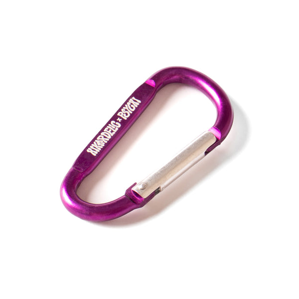 A purple carabiner with hikerdelic x psychi logo in white on the side