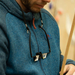 A pair of belay glasses hang around a climbers neck while he secures a climbing rope to his harness at Depot climbing Manchester