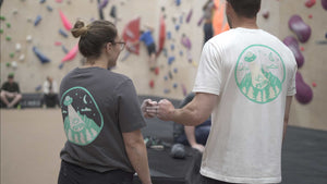 Two climbers bumping fists in front of a bouldering wall in Manchester.