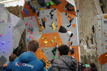 An indoor lead climbing competition with athlete's climbing and spectators