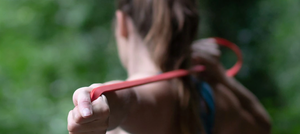 A woman stretches a psychi resistance yoga band behind her back as she warms up for climbing