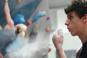 A rock climber rubbing his hands together with loose climbing chalk creating chalk dust at rockover climbing centre in Manchester