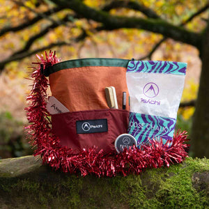 A rock climbing chalk bag and chalk gift bundle sits on a mossy rock surrounded by Christmas tinsel at Cratcliffe Tor in Derbyshire 
