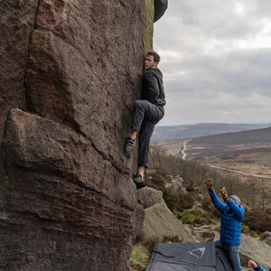 a boulderer clinging to a rock at Burbage South, Peak District
