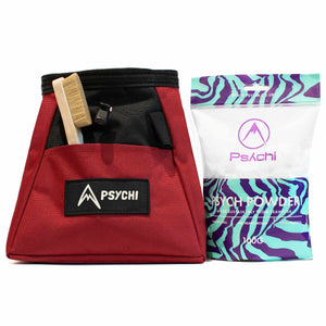 A red and black bouldering chalk bag with wooden brush, 100 gram bag of Psych Powder climbing chalk on a white background.
