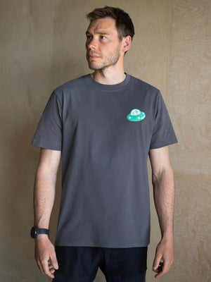 Bouldering apparel t-shirt modelled by man in a climbing gym with blurred wall background.