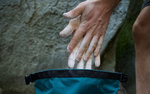A boulderer pulls his hands out of a bouldering bucket at Rubicon Crag in the Peak District