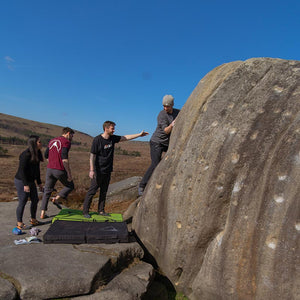 Four people bouldering on a huge boulder at burbage south in the peak district