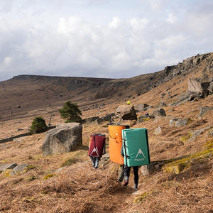 thee boulderers walk through stanage plantation carrying three pscyhi bouldering pads