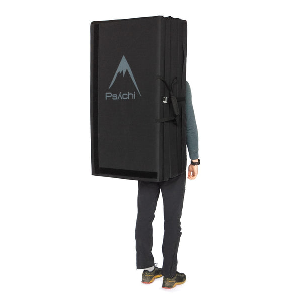 A man carrying a black triple fold bouldering mat on his back Psychi