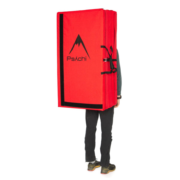 A man carrying a red triple fold bouldering mat on his back Psychi