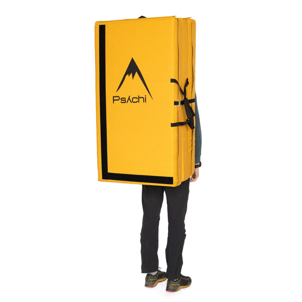 A man carrying a yellow triple fold bouldering mat on his back Psychi