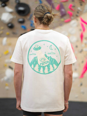 Unisex rock climbing clothing t shirt modelled in front of climbing wall by a female climber.