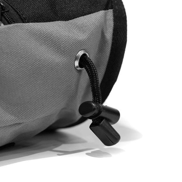 A Drawstring closure toggle on a light grey climbing chalk bag 