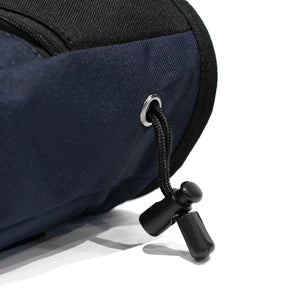 A Drawstring closure toggle on a navy blue climbing chalk bag 