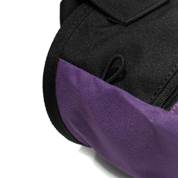An elastic climbing brush holder on a purple climbing chalk bag 