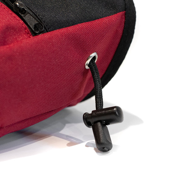 A Drawstring closure toggle on a red climbing chalk bag 