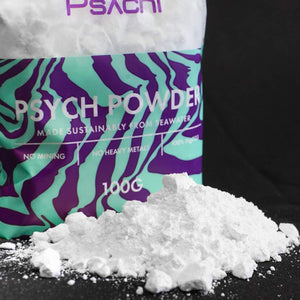 A pile of chunky sustainable climbing chalk sits on a black surface in front of a resealable bag of psych powder chalk