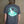 Unisex mountaineering t shirt modelled in front of wooden wall, featuring casual outdoor style.