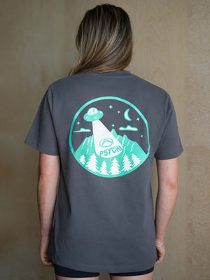 Unisex mountaineering t shirt modelled in front of wooden wall, featuring casual outdoor style.