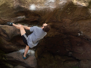 A climber climbing on a large boulder at Cratcliffe in the Peak District