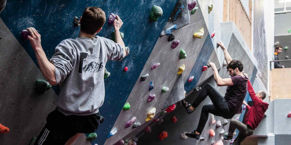 Three male climbers on an indoor climbing wall at Rockover Climbing Centre, Manchester