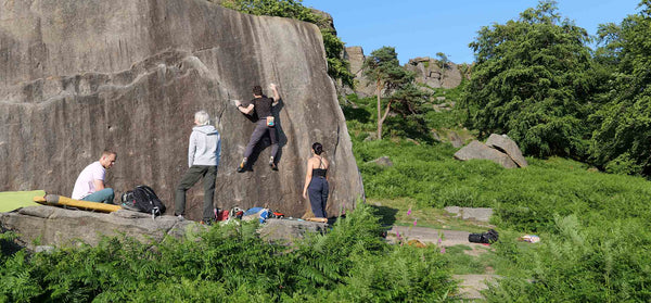 A group of boulderers bouldering on an outdoor rock face at stanage