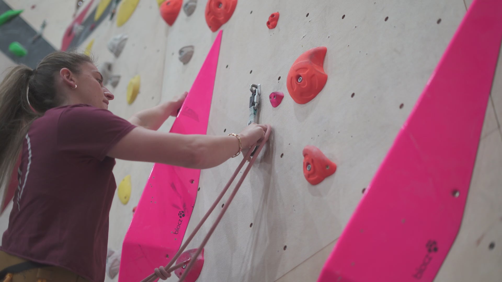 Two climbers rope climbing are using a black belay bucket to organise their climbing rope while belaying at a climbing centre in Manchester