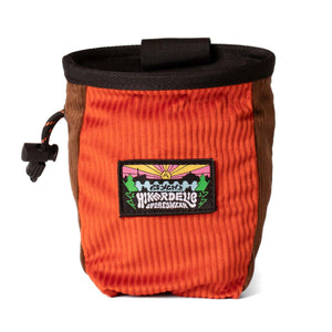 An orange and brown corduroy climbing chalk bag with a black waist strap. Featuring a hikerdelic and psychi logo mountain scene patch