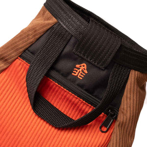 An orange mushroom logo embroidered onto a rock climbing chalk bucket.