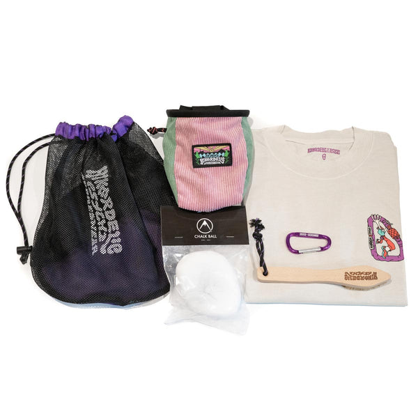 A teal and pink climbing chalk bag and chalk bundle, with climbing shoe bag, wooden brush, chalk ball, t-shirt and purple carabiner.