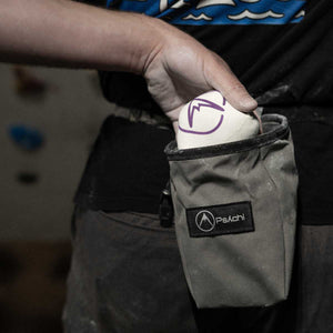 Climber holding a refillable chalk ball in a chalk bag with a visible psychi logo.