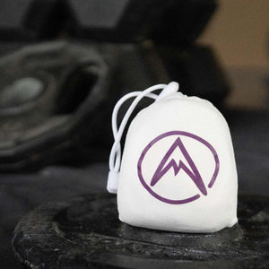 A refillable chalk ball sitting on a dumbbell at a gym.