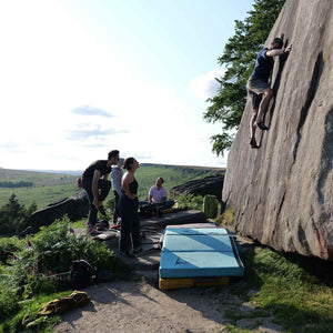 A group of boulderers watching their friend climb at Stanage Edge, Peak District