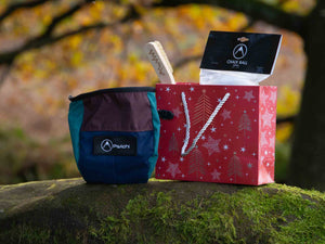 A sustainable rock climbing gift bundle in a red christmas gift bag sits on a rock at Cratcliffe, Yorkshire