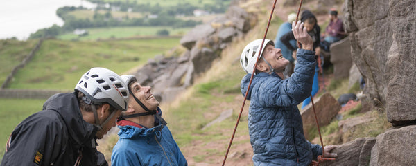 A group of friends on a stag do look up a rock face at Castle Naze in the peak district, while being instructed by a qualified climbing instructor.