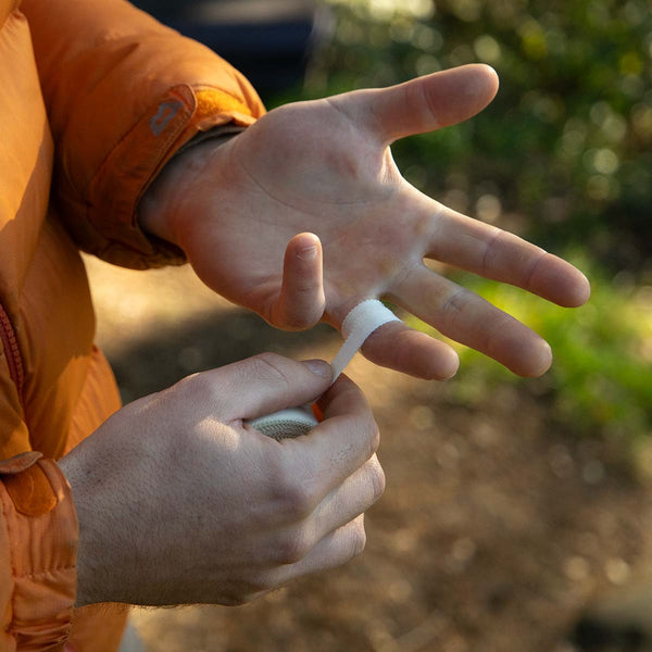 A climber wrapping zinc oxide cotton tape around his fingers at Cratcliffe, Yorkshire