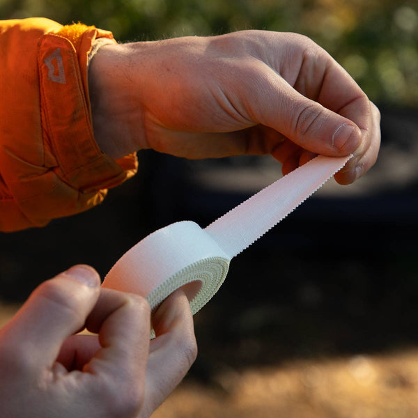 A climber pulls a length of zinc oxide cotton tape from a roll at Cratcliffe, Yorkshire