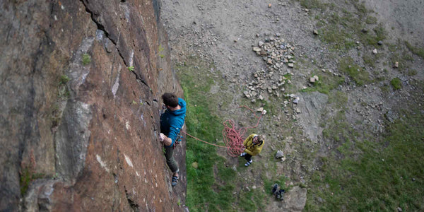 A male climber ascends a rock face with a saftey rope and a woman belaying at Hobson's Moor Quarry 