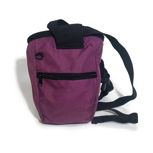 Rear of purple chalk bag with zipped pocket, a black waist strap and a black drawstring closure.