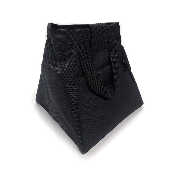 The rear of a black bucket bag, with zipped pocket, a wide base and black carry handle.