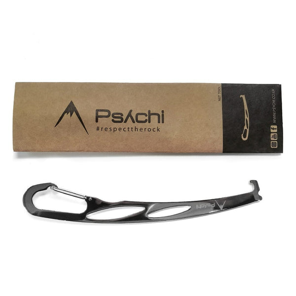 Thin silver metal nut remover, with two holes in the shaft, carabiner clip at the end and black and brown cardboard sleeve.